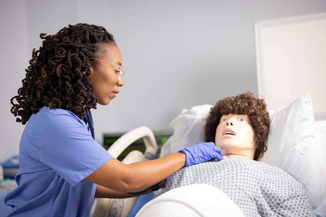 nursing student working with sim manikin