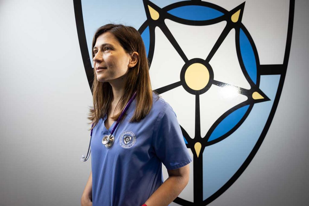 nursing student standing by wall with NDMU logo