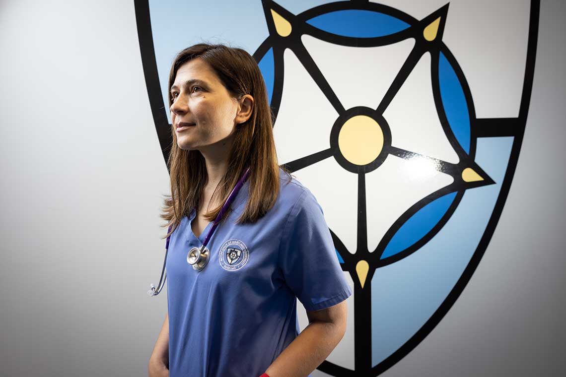 nursing student standing by wall with NDMU logo